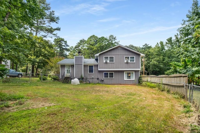 back of house with entry steps, a yard, a fenced backyard, and a chimney