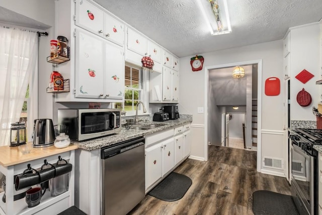 kitchen featuring dark wood-style floors, visible vents, a sink, stainless steel appliances, and white cabinetry