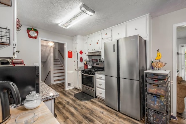 kitchen featuring dark wood-style floors, visible vents, under cabinet range hood, appliances with stainless steel finishes, and white cabinetry