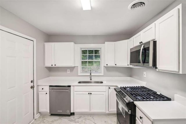 kitchen with appliances with stainless steel finishes, white cabinetry, and sink