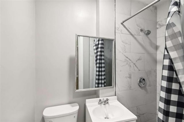 bathroom with vanity, toilet, and a tile shower