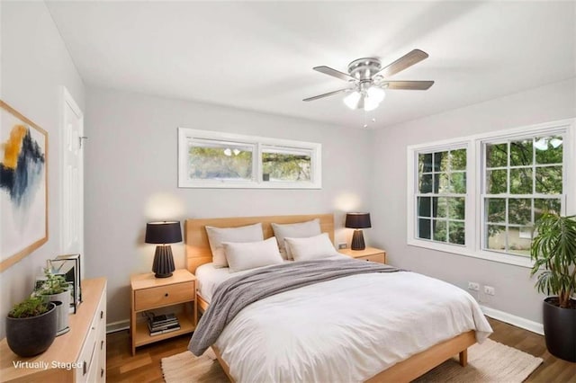 bedroom with ceiling fan, dark hardwood / wood-style flooring, and multiple windows