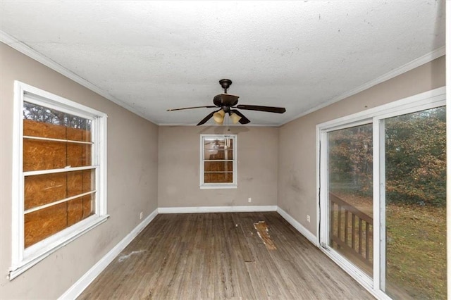 spare room with a healthy amount of sunlight, wood-type flooring, a textured ceiling, and ornamental molding