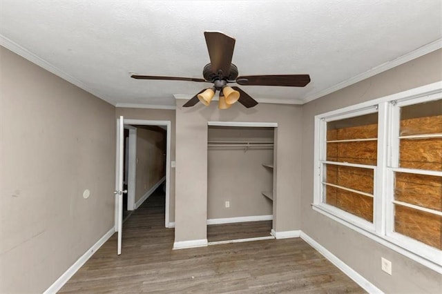 unfurnished bedroom with crown molding, dark hardwood / wood-style floors, ceiling fan, and a closet