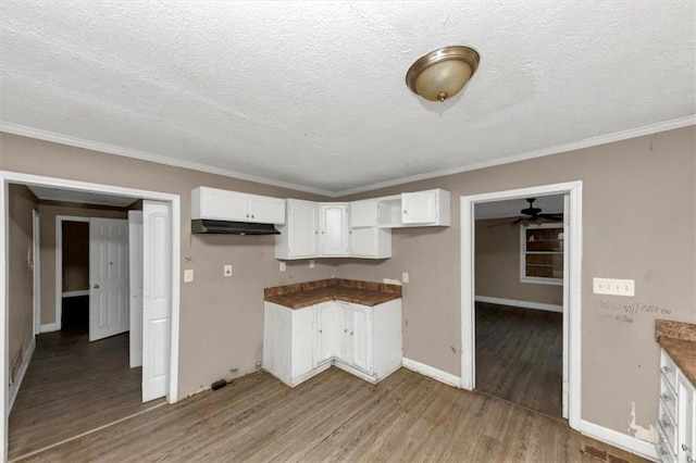 kitchen with white cabinetry, crown molding, a textured ceiling, and light wood-type flooring