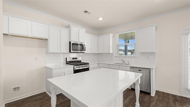 2939 Champions Way, Loganville, GA 30052 - kitchen with appliances with stainless steel finishes, a breakfast bar, white cabinetry, dark wood-style floors, and a kitchen island