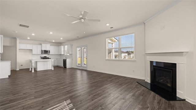 2939 Champions Way, Loganville, GA 30052 - unfurnished living room featuring dark wood-type flooring, recessed lighting, ceiling fan, a glass covered fireplace, and ornamental molding