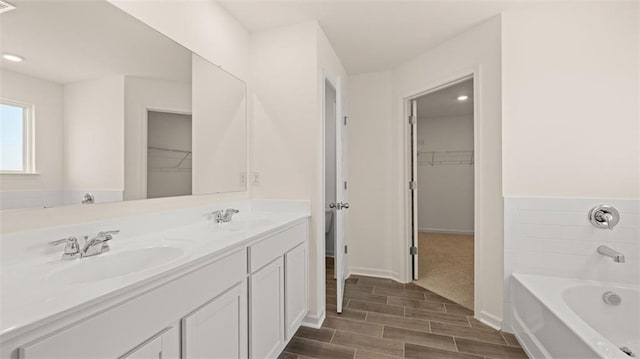 2939 Champions Way, Loganville, GA 30052 - bathroom with a spacious closet, double vanity, a bath, wood finished floors, and recessed lighting