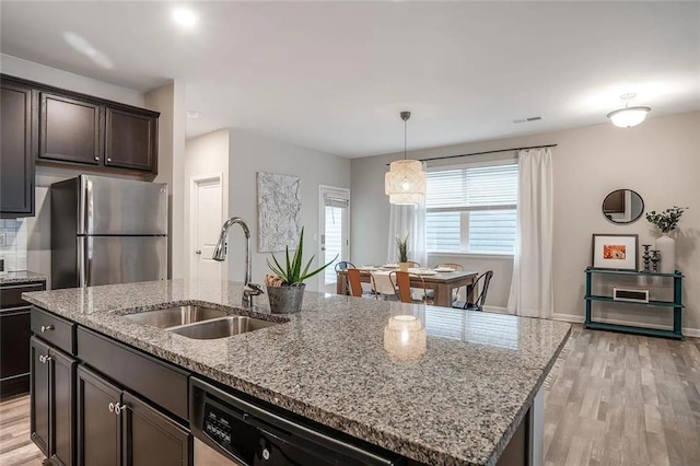 kitchen with a sink, dishwashing machine, light wood-style floors, and freestanding refrigerator