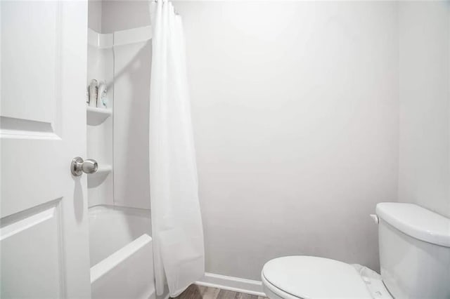 bathroom with shower / bathtub combination with curtain, toilet, wood finished floors, and baseboards