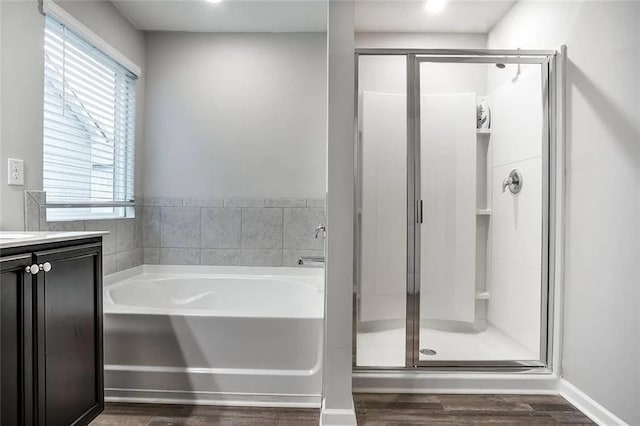 full bathroom featuring baseboards, a garden tub, a stall shower, wood finished floors, and vanity