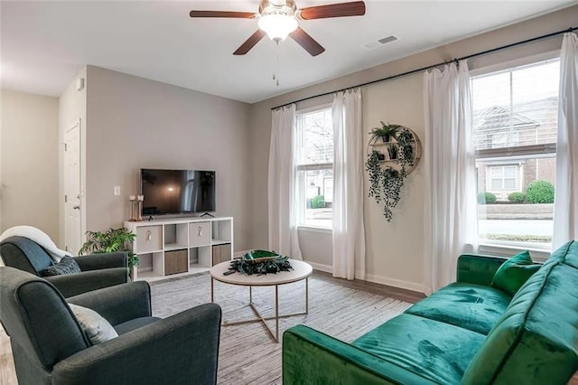 living area featuring visible vents, a ceiling fan, baseboards, and wood finished floors