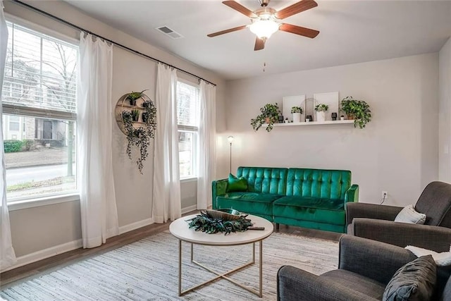 living room with visible vents, ceiling fan, baseboards, and wood finished floors