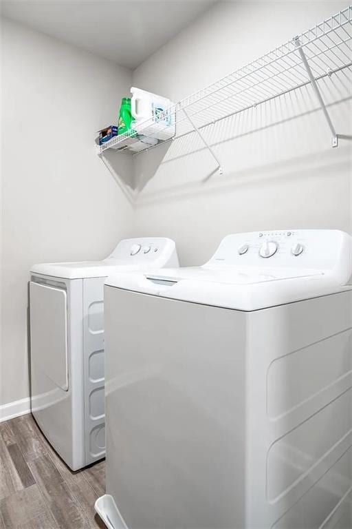 clothes washing area featuring laundry area, wood finished floors, and washing machine and clothes dryer