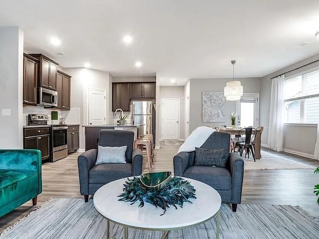 living area featuring light wood-style flooring, recessed lighting, and baseboards