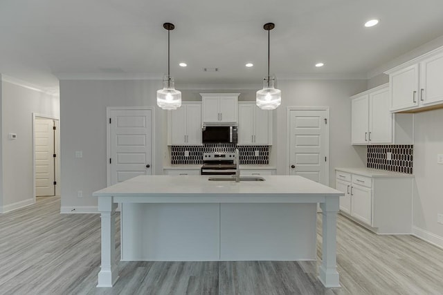 kitchen featuring white cabinetry, stainless steel appliances, backsplash, decorative light fixtures, and a center island with sink