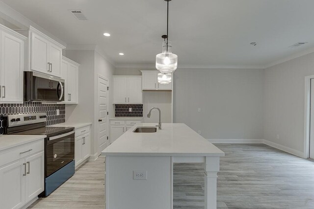 kitchen with a center island with sink, white cabinets, and appliances with stainless steel finishes