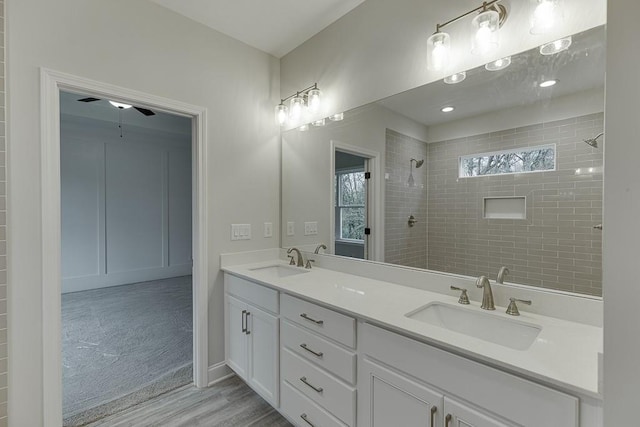 bathroom featuring hardwood / wood-style floors, ceiling fan, a tile shower, and vanity