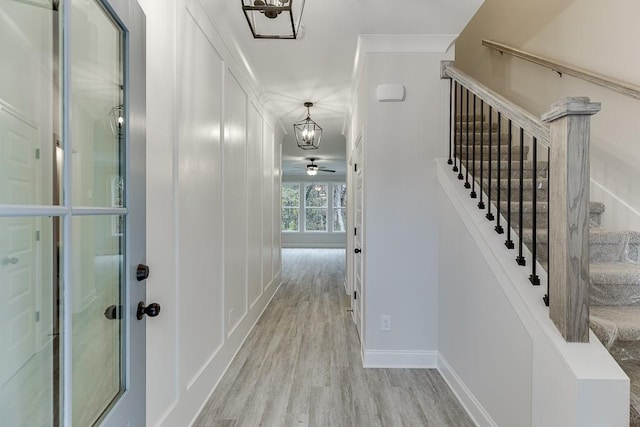 hall with light hardwood / wood-style floors and an inviting chandelier