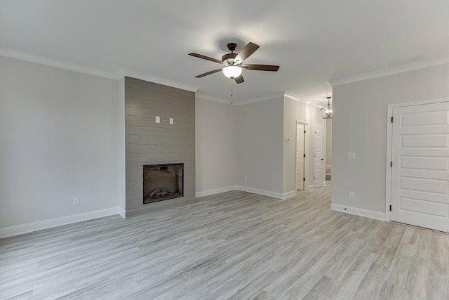 unfurnished living room with crown molding, a large fireplace, ceiling fan with notable chandelier, and light wood-type flooring