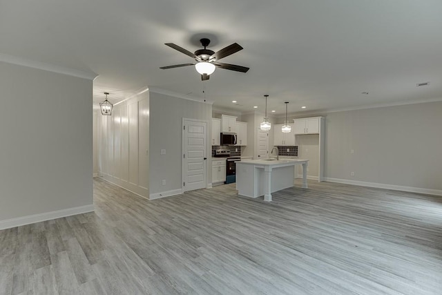 kitchen with appliances with stainless steel finishes, a center island with sink, white cabinets, light hardwood / wood-style floors, and hanging light fixtures