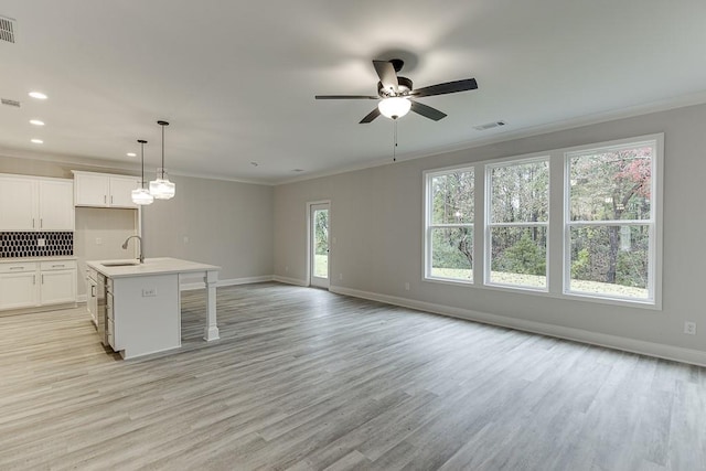 kitchen with white cabinetry, a kitchen island with sink, sink, and a healthy amount of sunlight