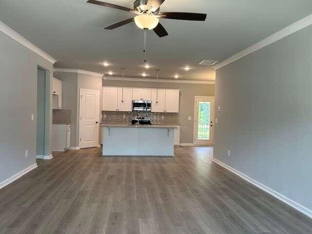 kitchen with decorative backsplash, appliances with stainless steel finishes, a kitchen island with sink, crown molding, and white cabinets