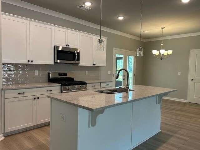 kitchen with white cabinets, appliances with stainless steel finishes, and a kitchen island with sink