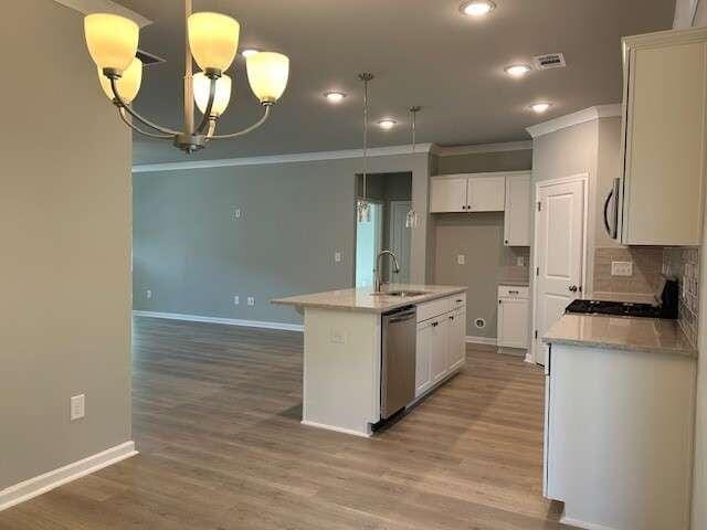 kitchen featuring sink, an inviting chandelier, a center island with sink, white cabinets, and appliances with stainless steel finishes