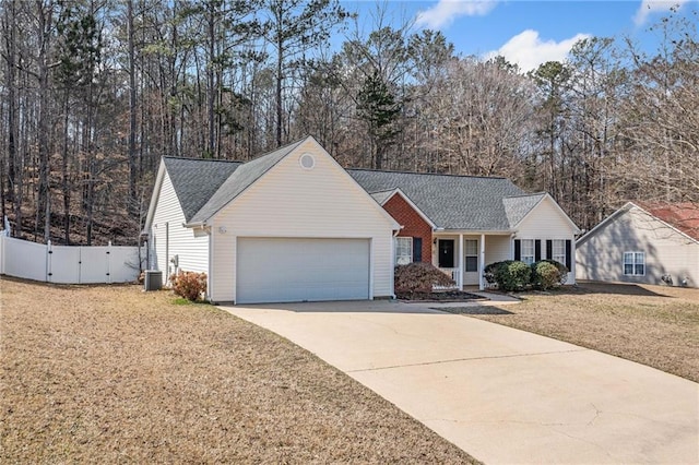 ranch-style home with a garage, concrete driveway, fence, a front lawn, and central AC