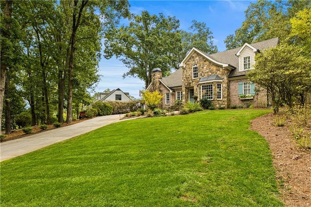 traditional-style home featuring driveway, stone siding, and a front yard