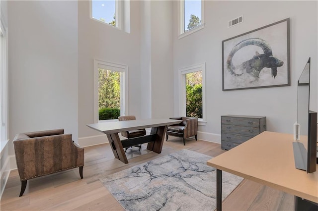 office space featuring plenty of natural light, a high ceiling, wood finished floors, and baseboards
