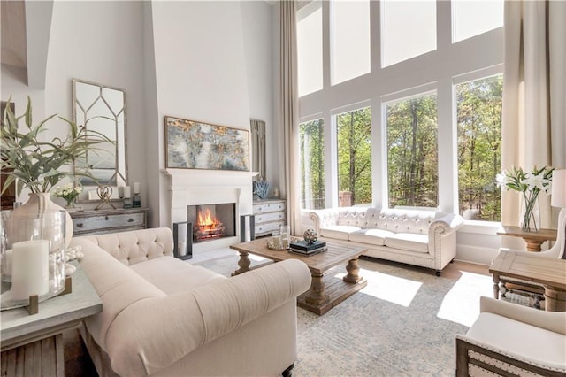 living room featuring a high ceiling and a lit fireplace