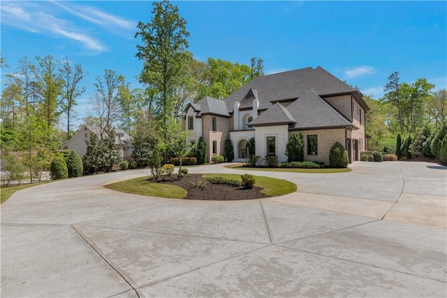 french country home featuring curved driveway and a garage