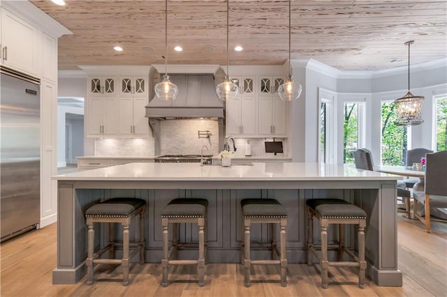 kitchen featuring stainless steel built in fridge, custom exhaust hood, wood ceiling, white cabinetry, and light countertops