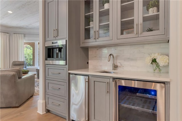 indoor wet bar featuring wine cooler, refrigerator, light wood-style flooring, backsplash, and crown molding