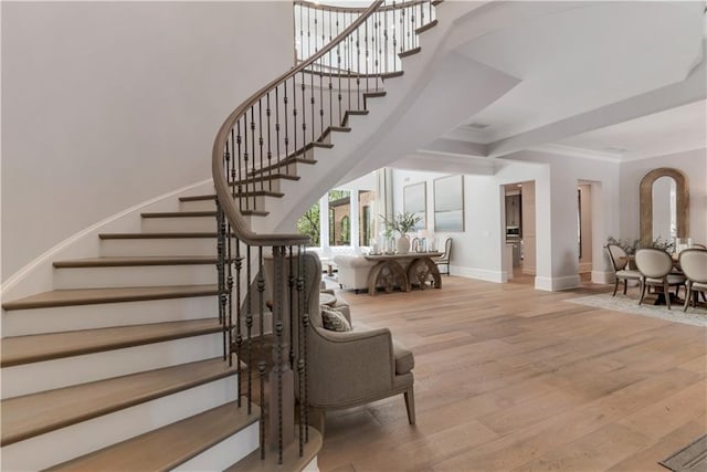 staircase featuring baseboards, wood finished floors, and crown molding