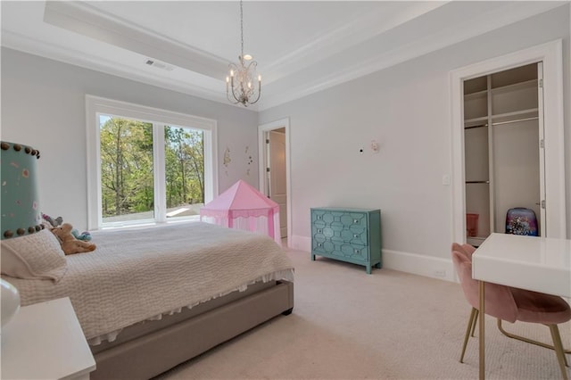 bedroom featuring a chandelier, carpet floors, a tray ceiling, baseboards, and a spacious closet