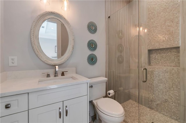 full bathroom featuring a shower stall, toilet, and vanity