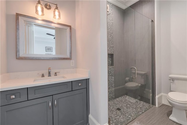 bathroom featuring toilet, a stall shower, vanity, and baseboards