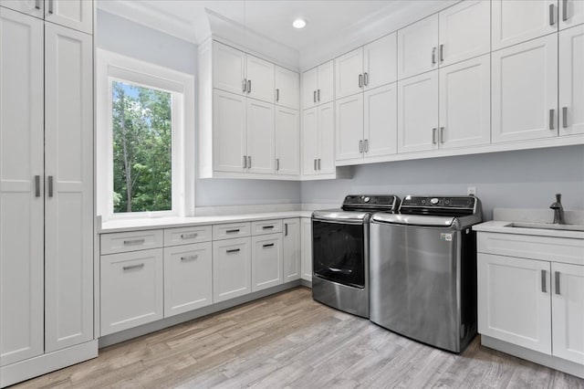 washroom featuring cabinet space, washer and clothes dryer, light wood-style flooring, recessed lighting, and crown molding