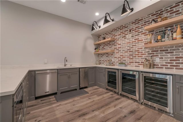 indoor bar featuring beverage cooler, dishwasher, light wood-style floors, brick wall, and recessed lighting