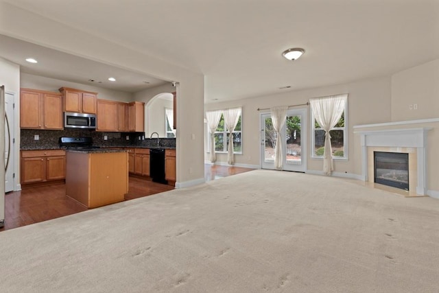 kitchen featuring a center island, backsplash, a fireplace with flush hearth, open floor plan, and black appliances