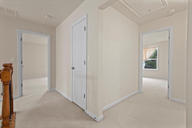 corridor with light carpet, visible vents, attic access, and baseboards