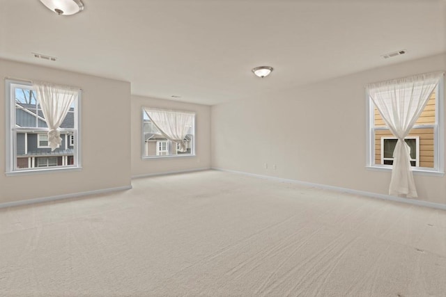 unfurnished room featuring light colored carpet, visible vents, and baseboards