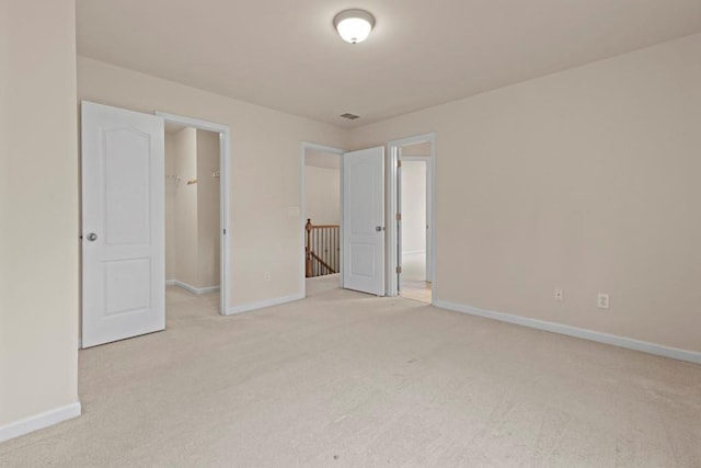 unfurnished bedroom with carpet floors, a spacious closet, and baseboards