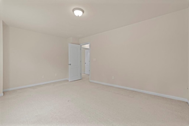 unfurnished room featuring light carpet and baseboards