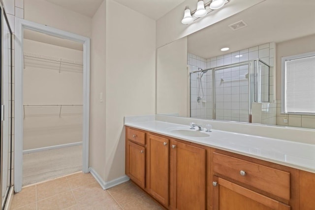 full bathroom with visible vents, a spacious closet, a stall shower, vanity, and tile patterned floors