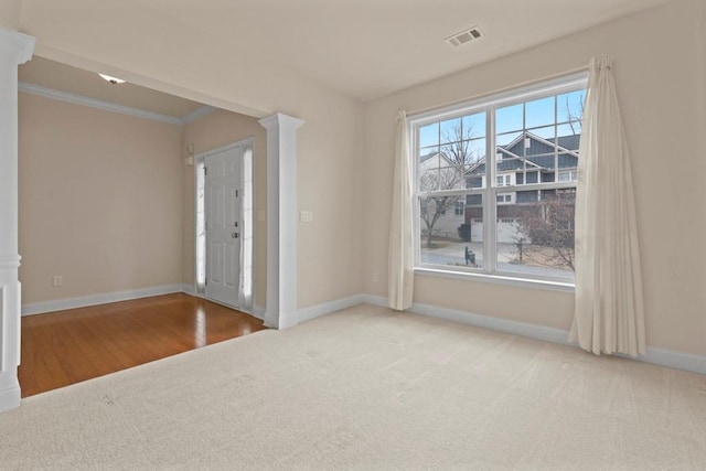 foyer entrance featuring ornate columns, visible vents, ornamental molding, carpet flooring, and baseboards