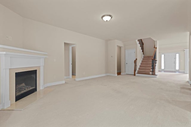 unfurnished living room with carpet floors, stairway, baseboards, and a premium fireplace